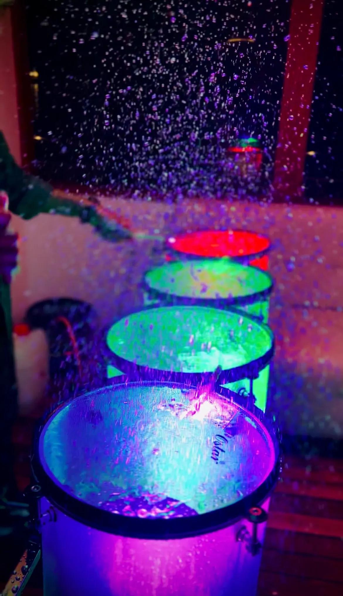 A vibrant and colorful scene aboard Minar Cruise, featuring illuminated drums and water droplets