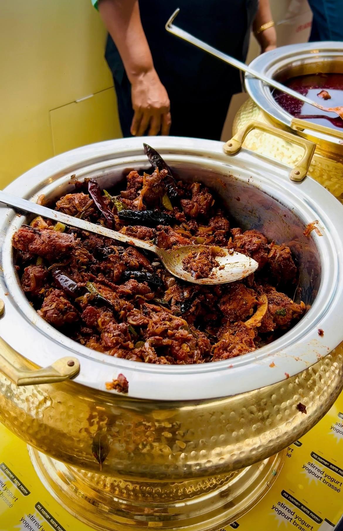 A close-up of a dish of spicy Indian chicken curry being served on a catamaran cruise